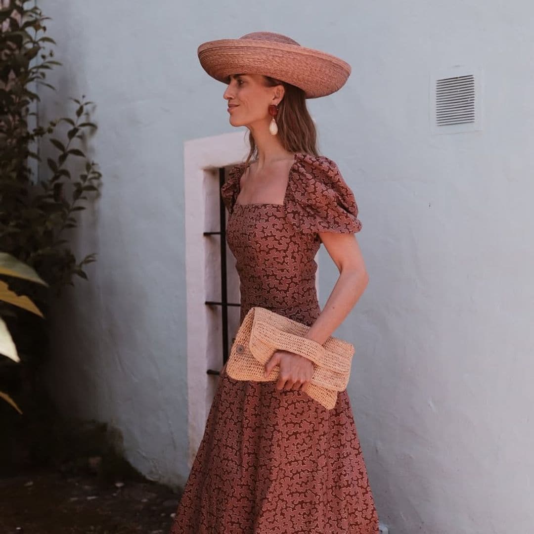 La diseñadora Carmen de la Puerta, muy acertada como invitada en Sevilla, con vestido estampado y sombrero de rafia
