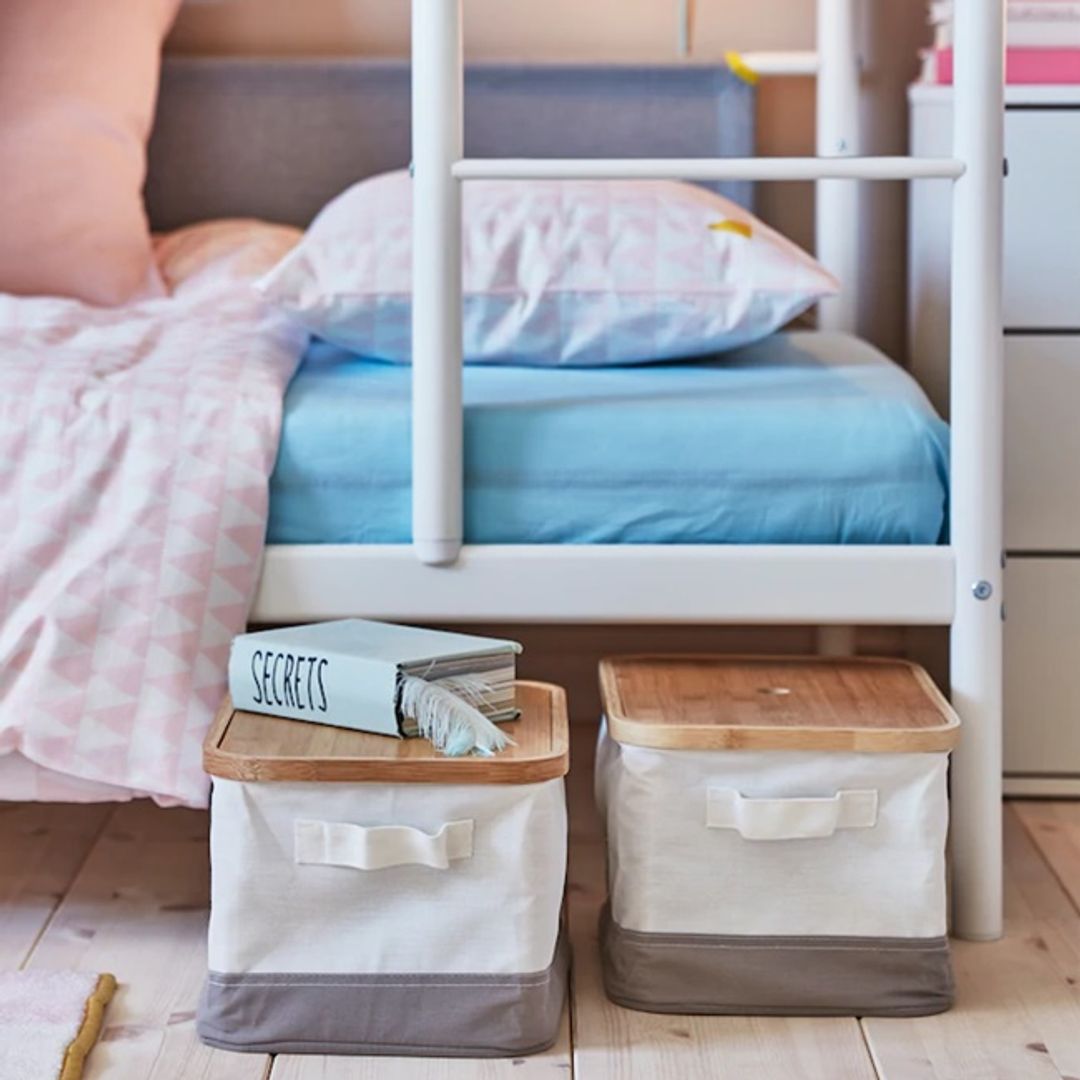 Cajas de almacenaje debajo de una cama infantil en forma de litera blanca.