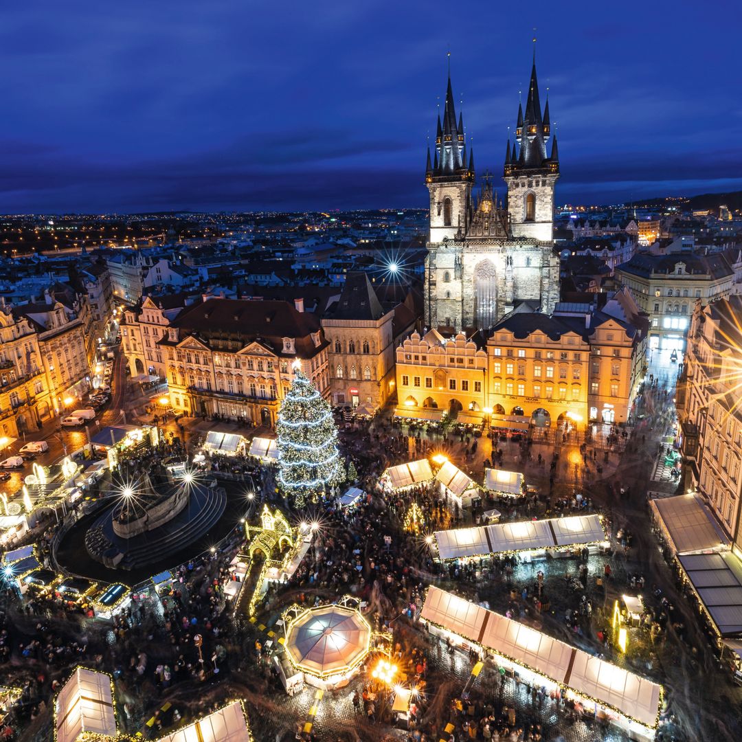 Vista nocturna de la ciudad con una multitud en la plaza del mercado, iluminada y llena de tiendas.
