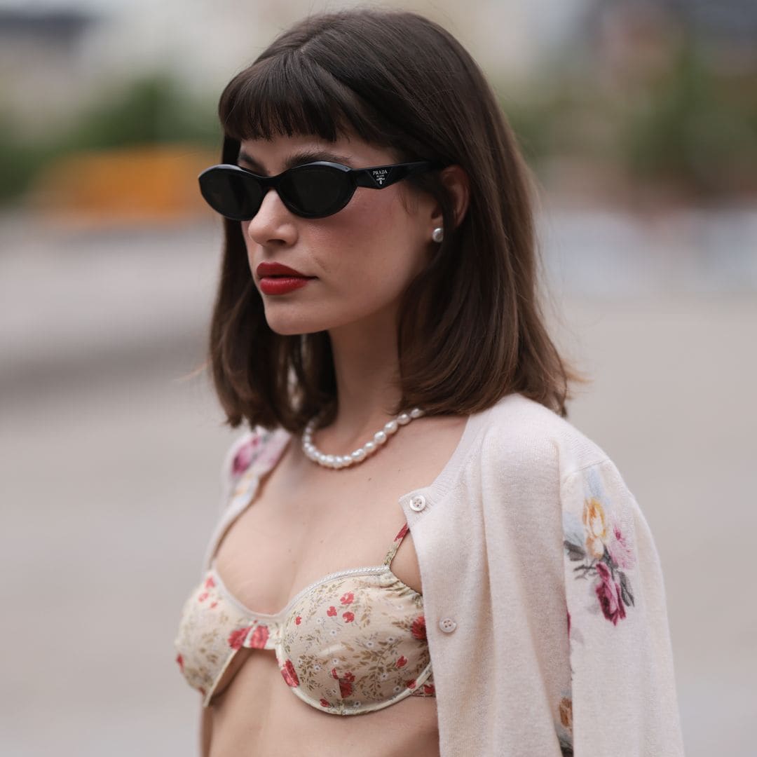 OPENHAGEN, DENMARK - AUGUST 08: Lea Naumann is seen wearing black oval cay-eye sunglasses from Prada; small silver round earrings; a pearl necklace; a sand-beige two-piece with red flower pattern from Prada, consisting of a bra, and a voluminous midi skirt; and a beige cardigan with multicolored flower pattern from Prada before the Rotate Show during day four of the Copenhagen Fashion Week (CPHFW) SS25 on August 08, 2024 in Copenhagen, Denmark. (Photo by Jeremy Moeller/Getty Images)