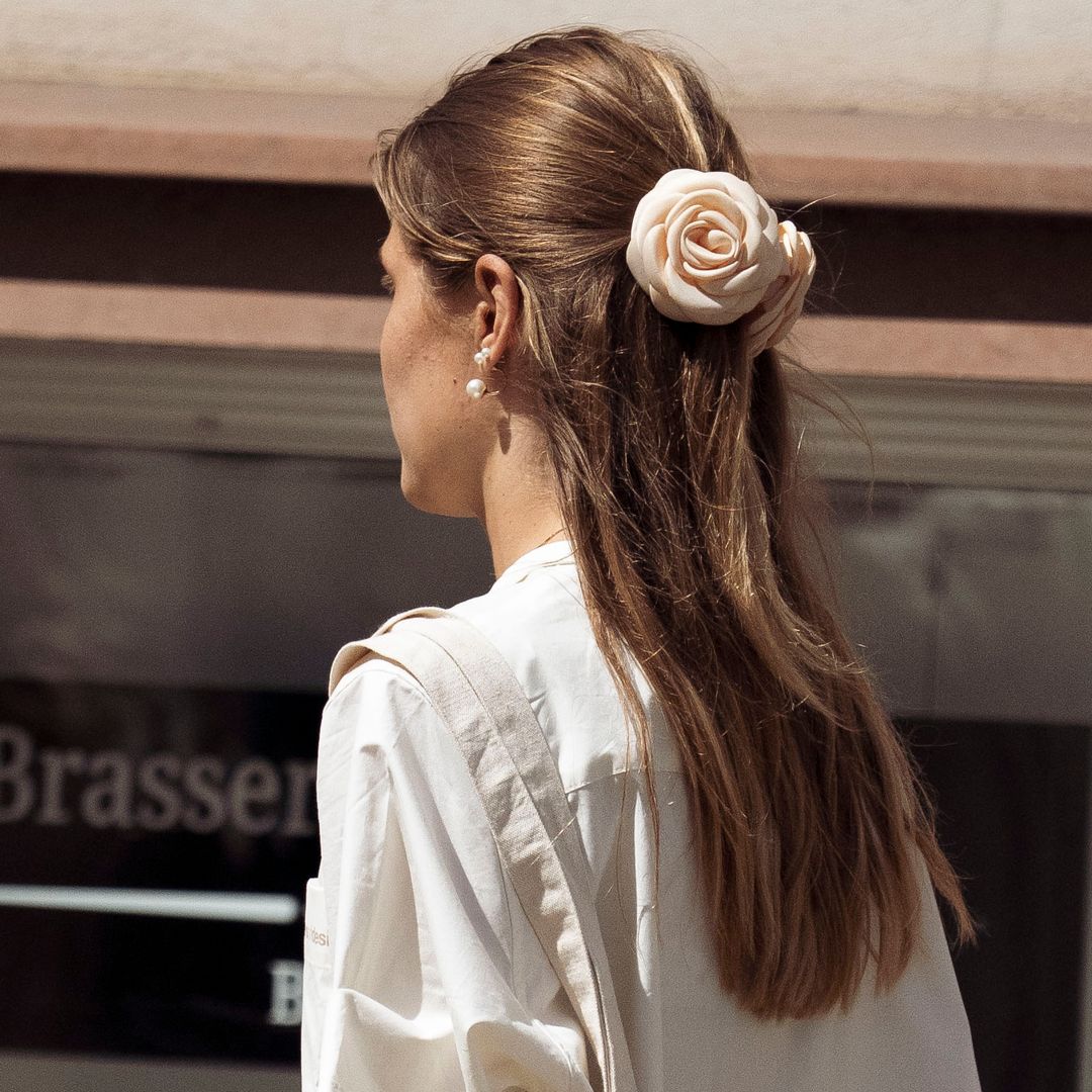 Invitada a la Semana de la Moda de Copenhague con pinza de flor blanca y pelo suelto
