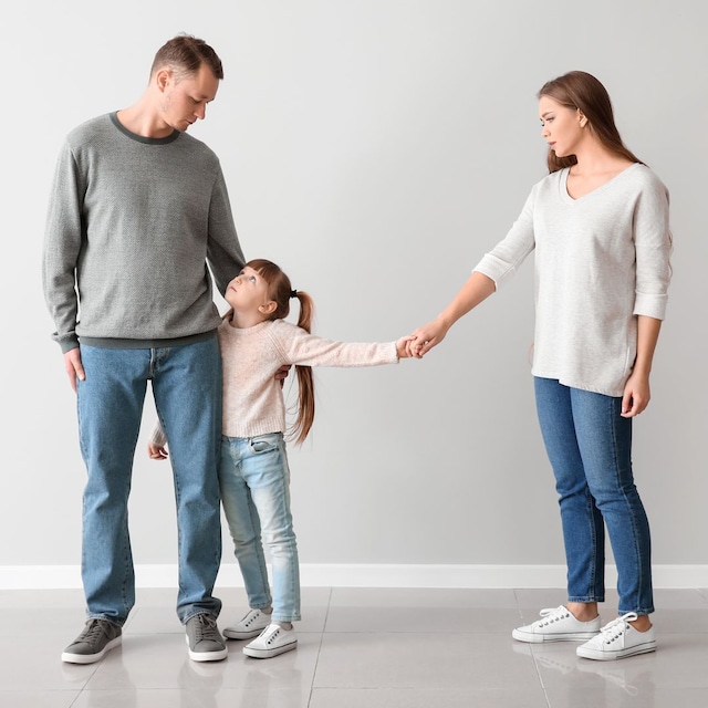 Madre da la mano a su hija que está con su padre en un contexto de divorcio