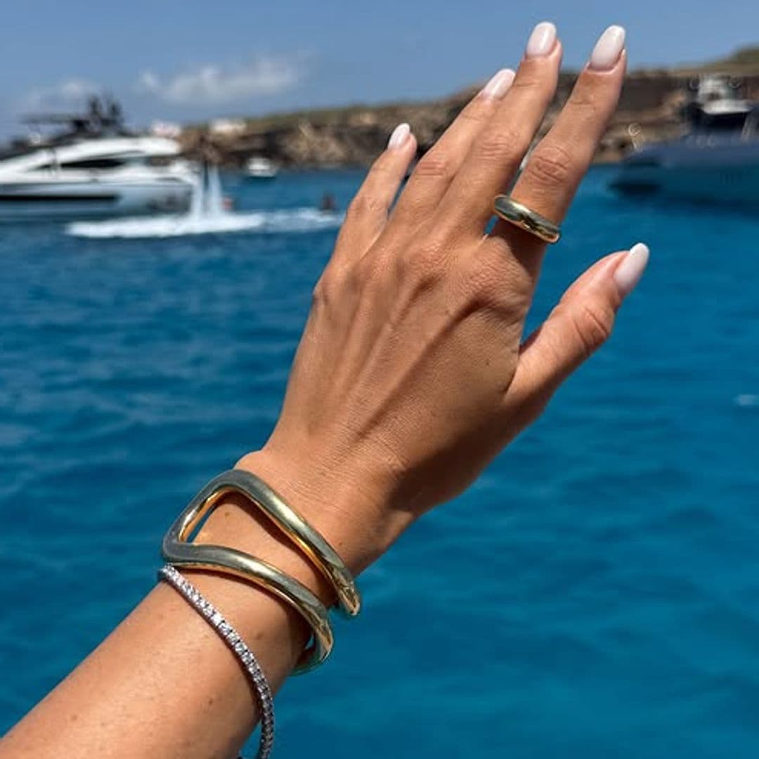 Manos con manicura blanca con el mar de fondo