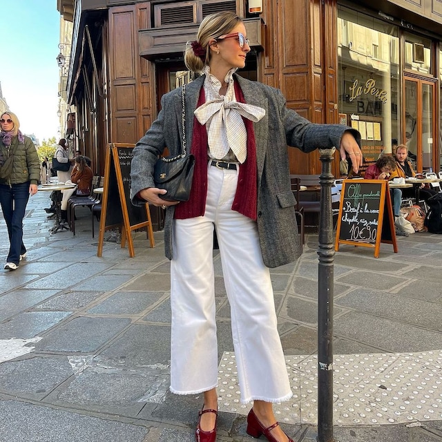Jeanne Ménard con camisa lazada y complementos burdeos