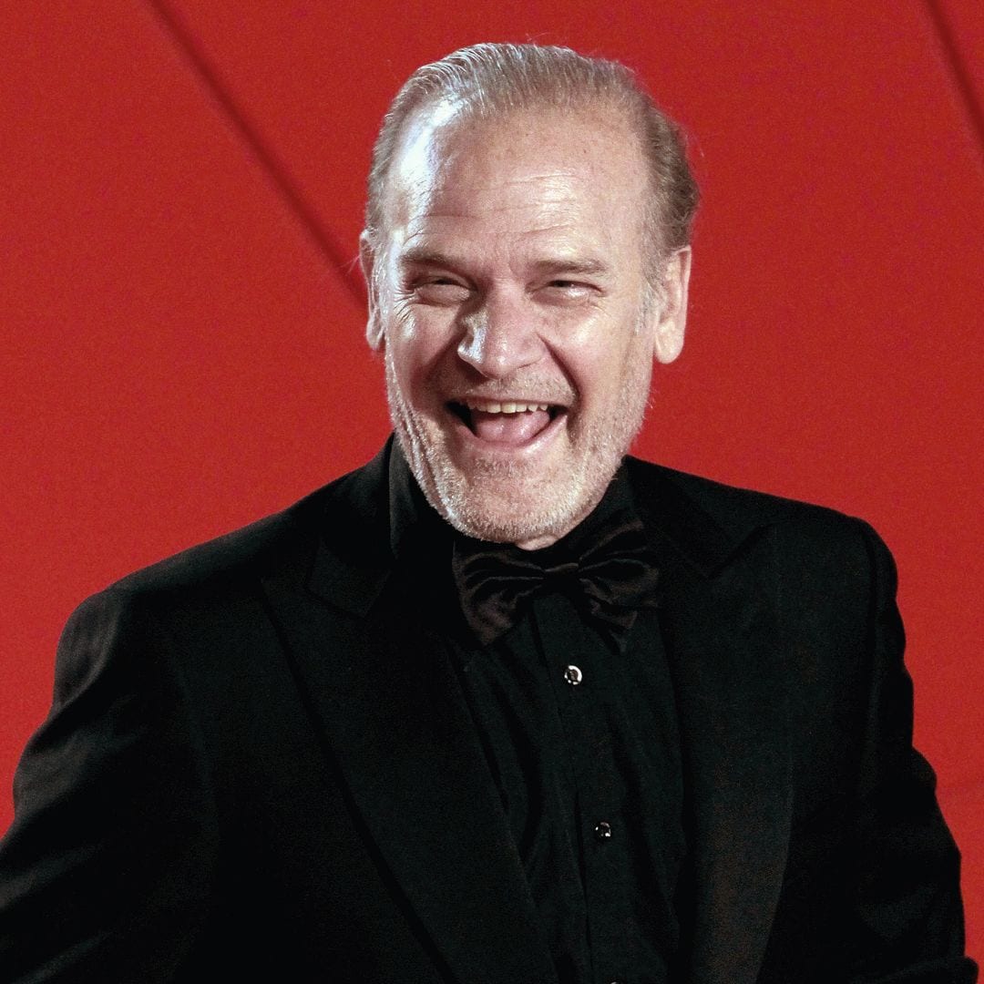 Lluís Homar sonriendo en un traje negro con pajarita.