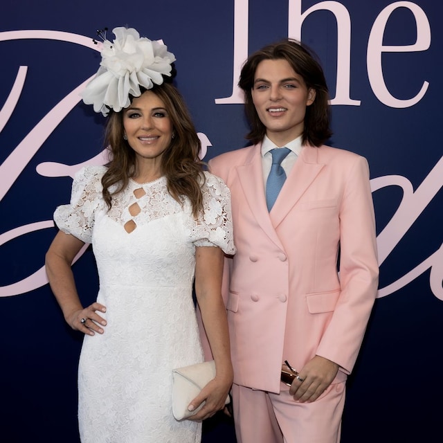 Plano medio de Elizabeth Hurley y Damian Hurley con vestido blanco y traje rosa