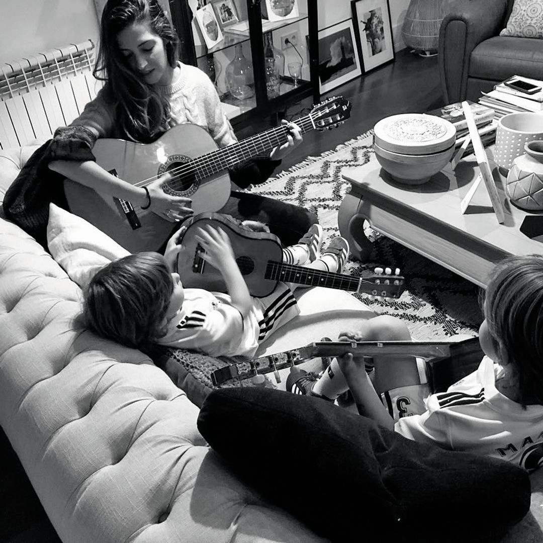 Sara Carbonero y sus hijos tocando la guitarra en el sofá 