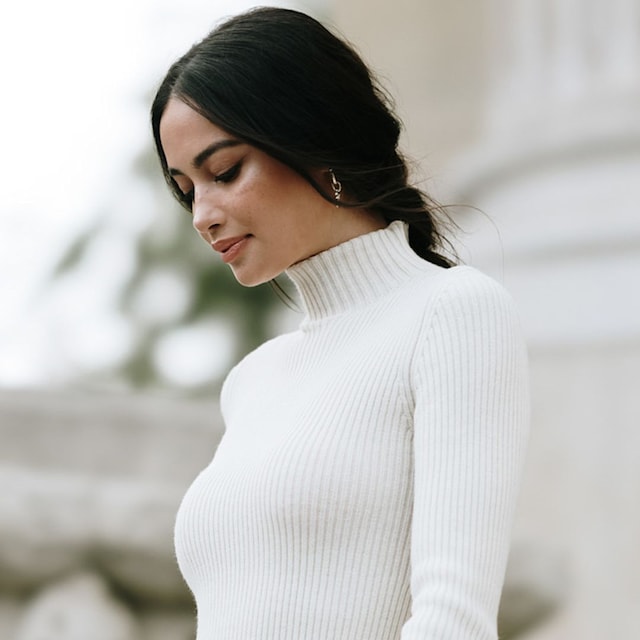 Mujer con pelo negro y jersey de cuello vuelto blanco en la Semana de la Moda de París