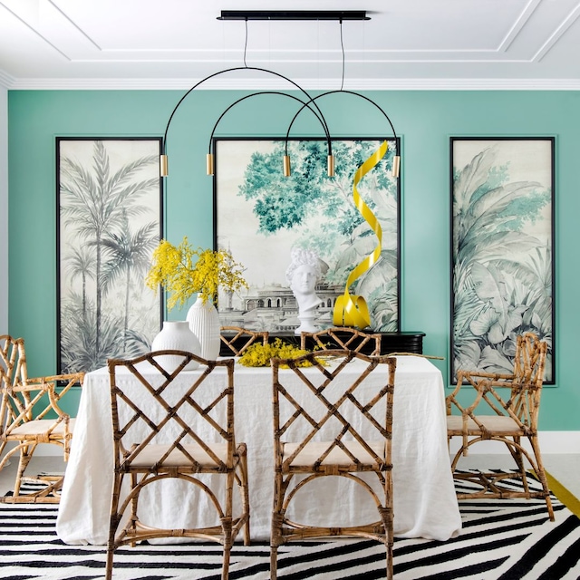 Comedor con pared verde, tríptico, alfombra a rayas negras y blancas, lámparas de techo