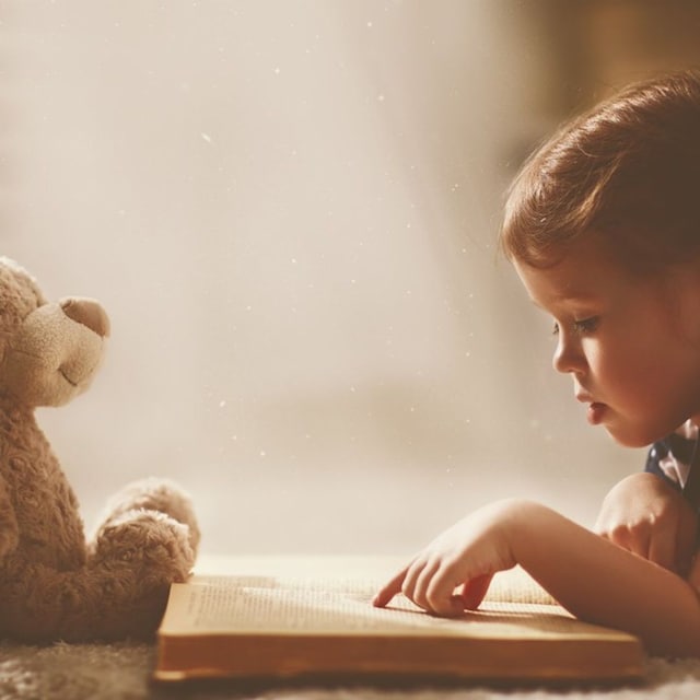 ni a leyendo cuento con oso de peluche en su habitaci n 