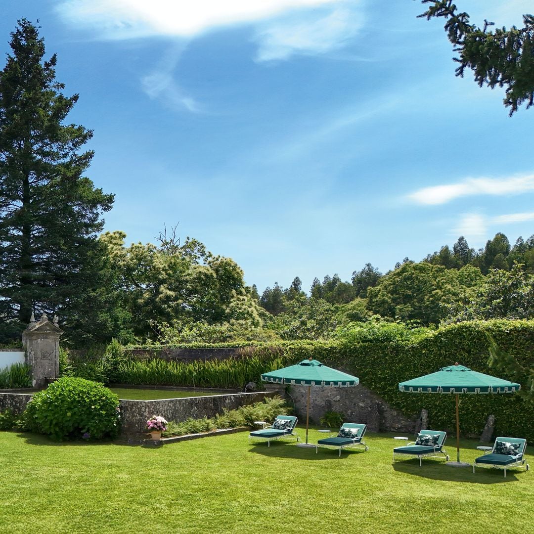Varias tumbonas de hierro, con cojines de Ralph Lauren, y sombrillas customizadas por Casa do Passadiço, en la zona de relax del jardín