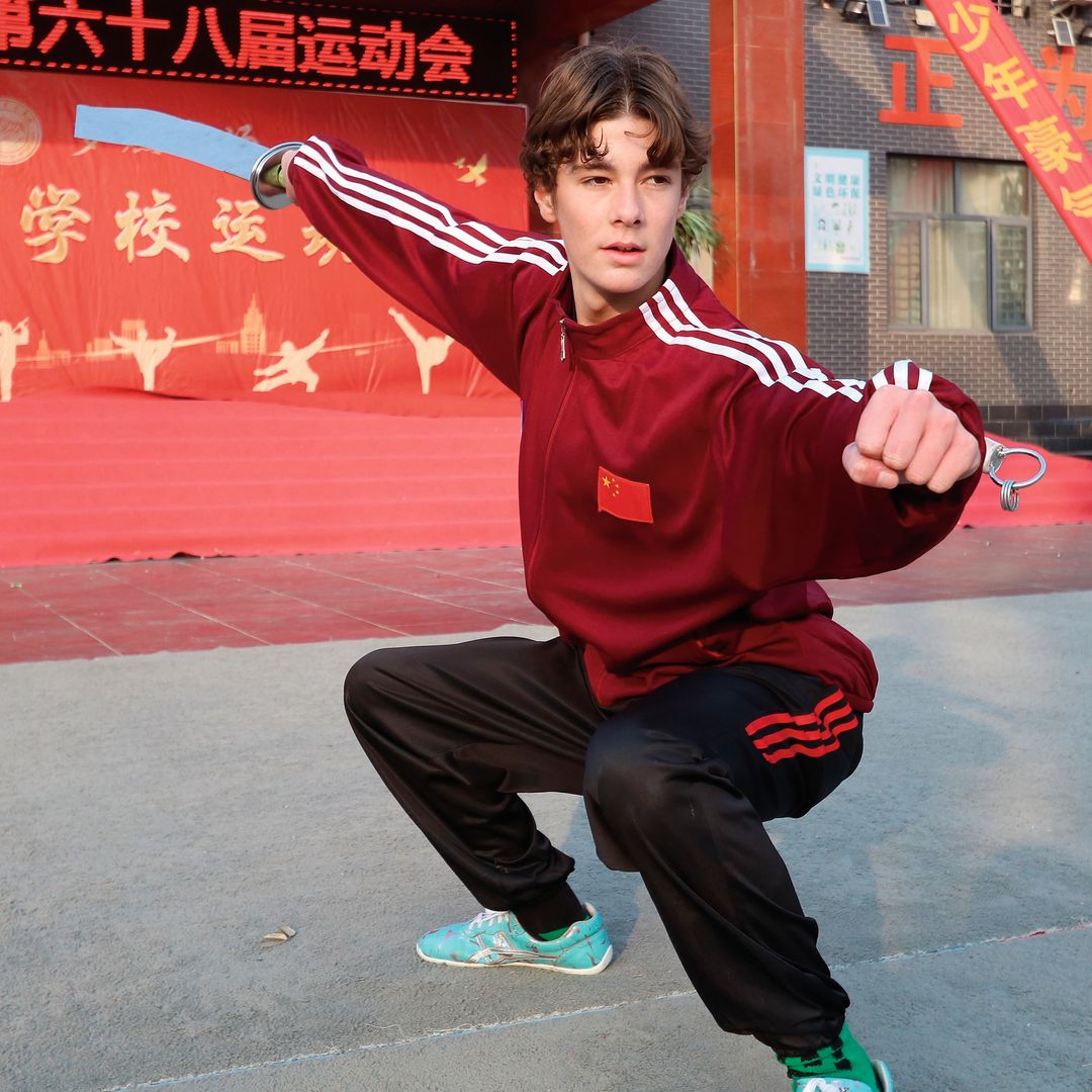 Simeón practicando artes marciales con traje deportivo rojo y negro