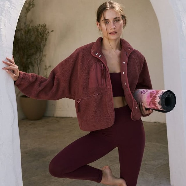 Mujer con ropa de deporte granate y esterilla