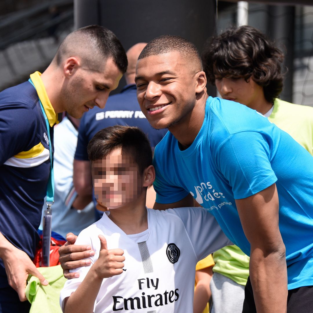 Kylian Mbappé sacándose una foto con un niño