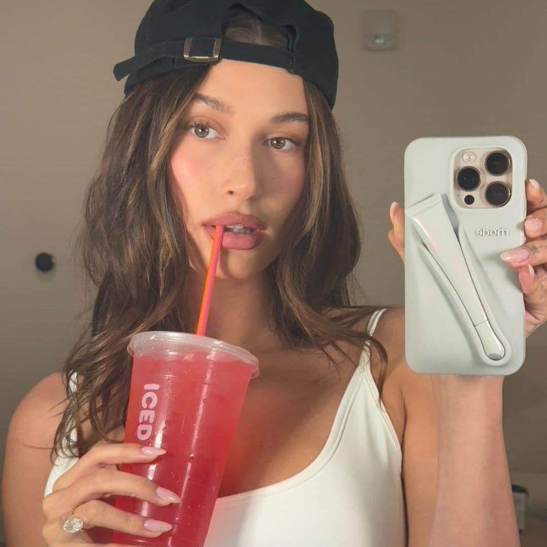 Hailey Bieber con gorra, bebida helada y top blanco