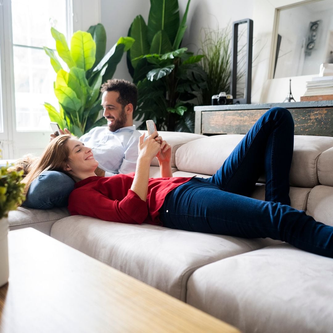 pareja descansando en el sofá, mirando sus móviles