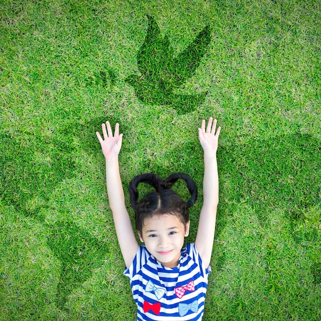 Niña tumbada en el suelo con fondo del mundo y paloma de la paz. Frases de paz para niños