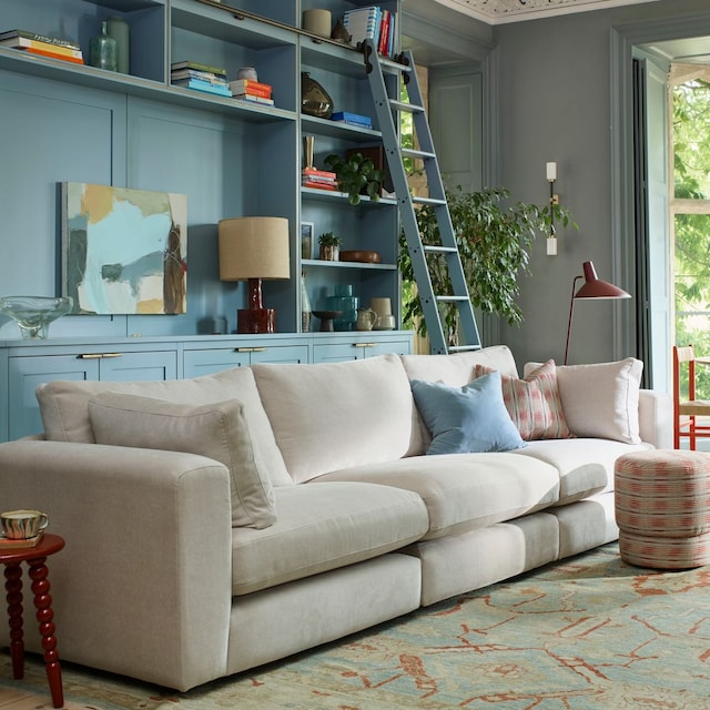 Salón con librería azul claro, alfombra de lana y sofá modular blanco