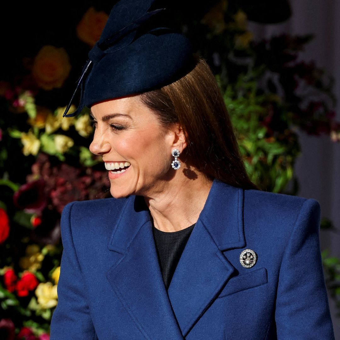 Kate Middleton con abrigo y tocado azules, pelo suelto liso y guantes en la bienvenida en el aeropuerto de Heathrow del presidente de la República Federal de Alemania,