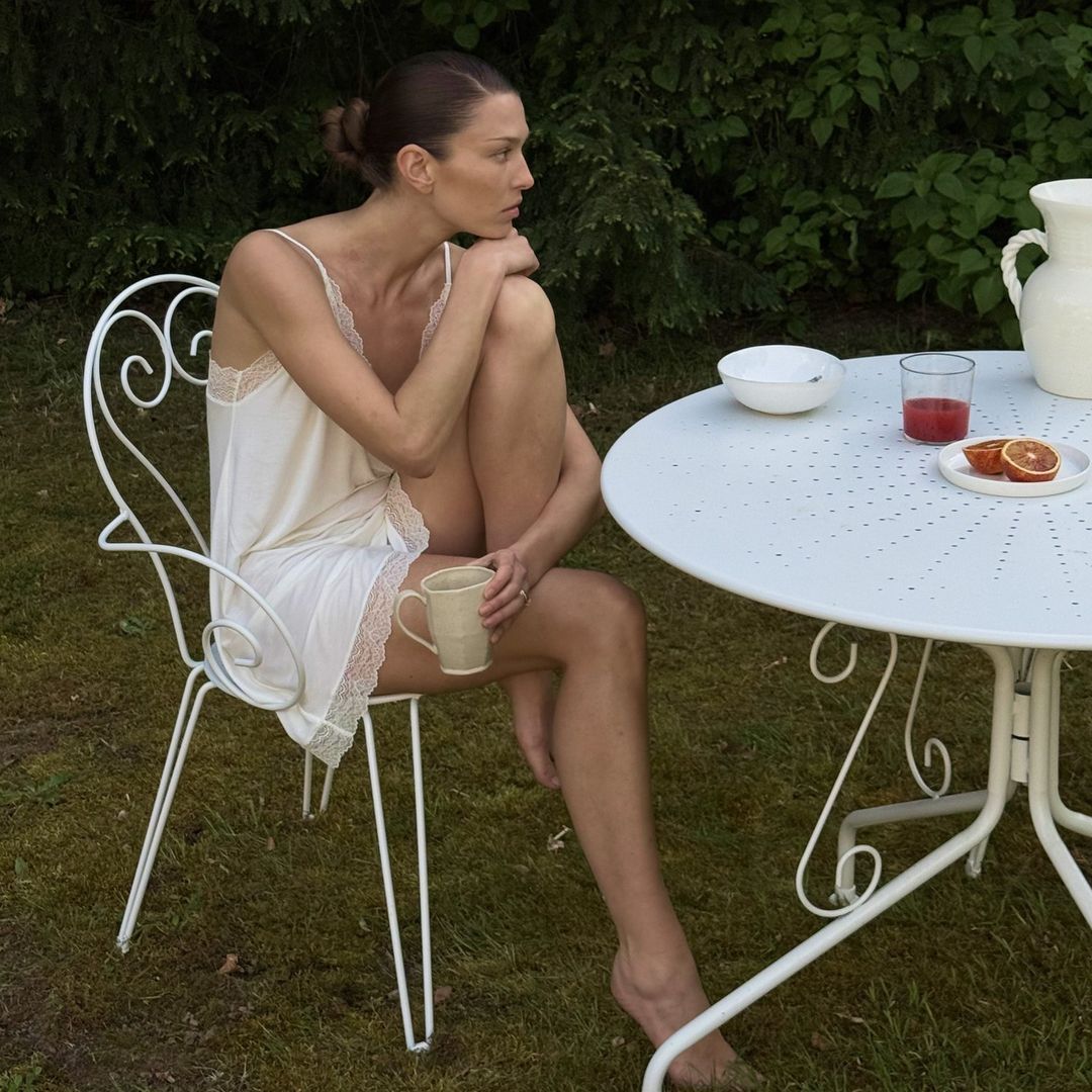 Modelo morena con camisón de Eberjey junto a una mesa blanca en un jardín