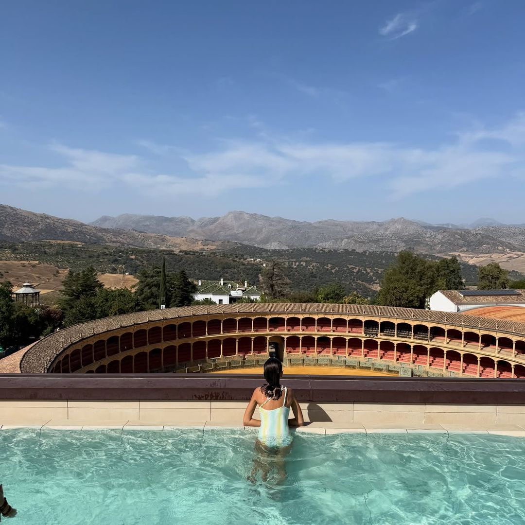 Carmen, la hija de Lourdes Montes, asomada desde la piscina a la plaza de toros de Ronda, Málaga,