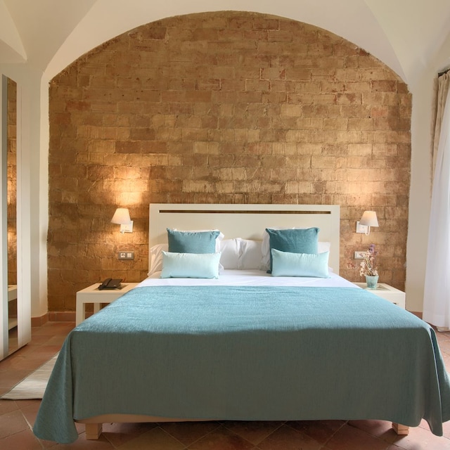 Dormitorio con pared de piedra y ropa de cama azul