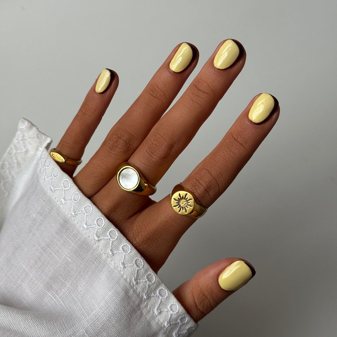 Manicura amarillo mantequilla con contorno en negro