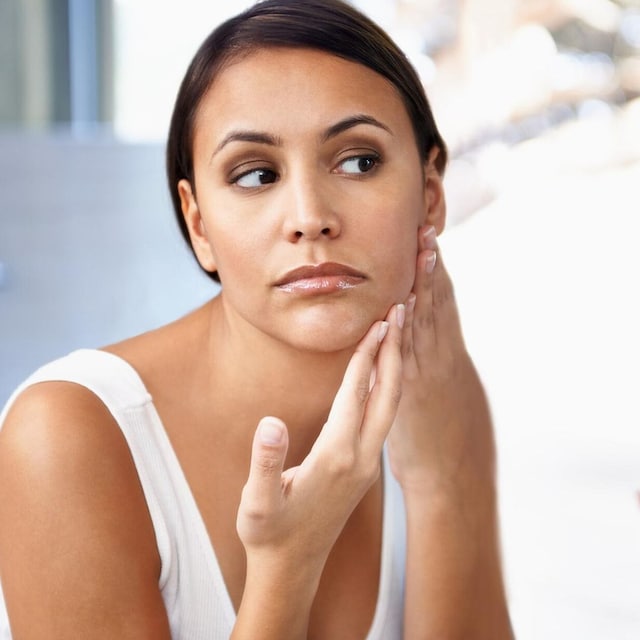 mujer observa su rostro en un espejo