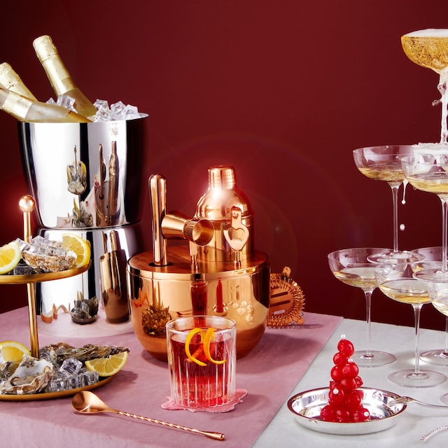 Mesa con coctelera, cubitera con botellas, copas de champán y ostras (San Valentín)