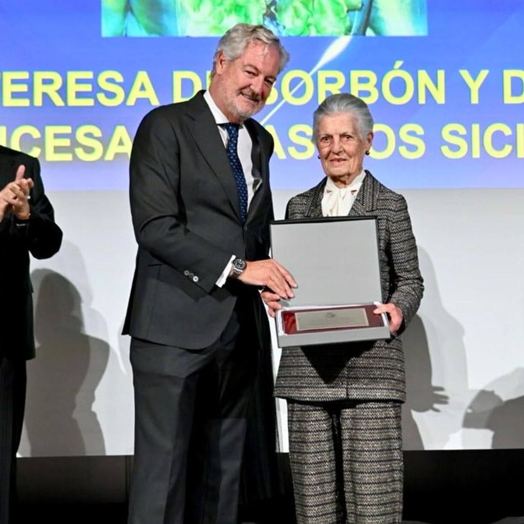 Cuatro personas en un escenario, una mujer recibe un premio de manos de un hombre