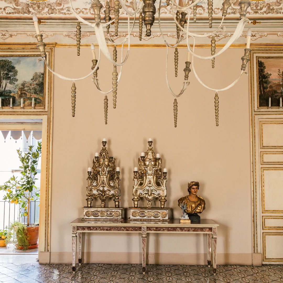 Una pareja de antorchas doradas de 1600, y medio busto del Rey Sol como emperador romano, colocados sobre una consola de Luis XVI en laca y vidrios, y sobrepuertas pintadas con frescos del siglo XVIII
