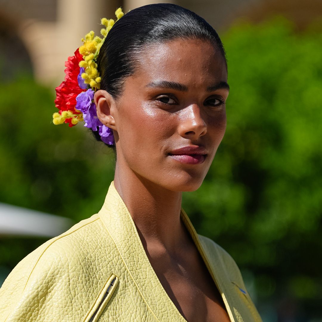 Tina Kunakey en la Semana de la Moda de París con cazadora amarilla y recogido con flores