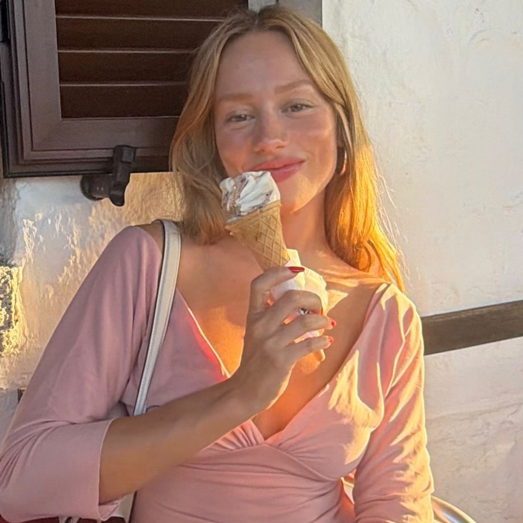 Ester Expósito con camiseta ros claro, falda blanca y comiendo un helado