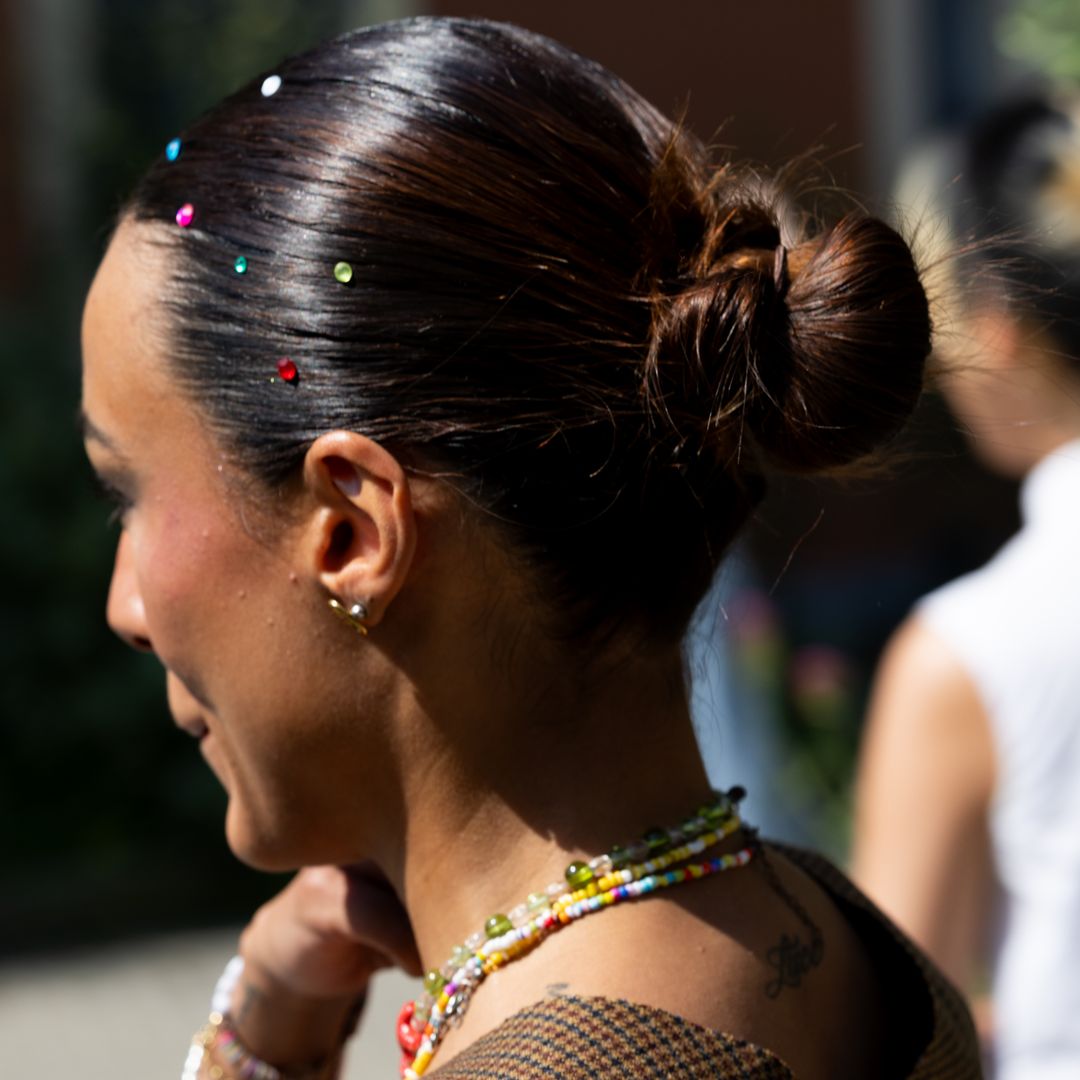 Mujer en Milán con moño bajo decorado con brillantes de colores