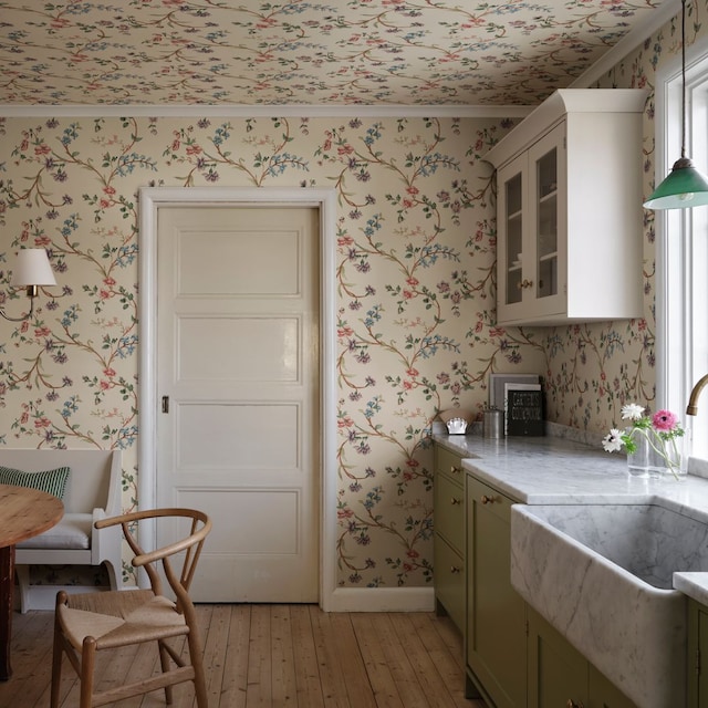 Cocina 'cottage' con papel pintado de flores, office con banco, fregadero retro y muebles de color verde claro
