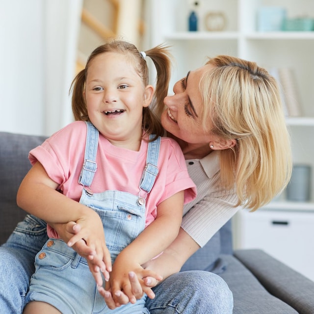 Madre abrazando feliz a su hija con síndrome de Down