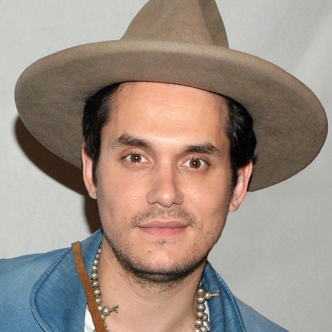 John Mayer con sombrero, chaqueta azul y collar de cuentas