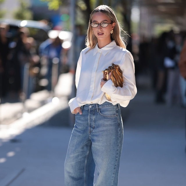 NEW YORK, NEW YORK - SEPTEMBER 08: Isabelle Allain is seen wearing oval glasses with a Havana frame from Miu Miu, square gold structured earrings, a white shirt tucked into bright wide-legged jeans, a shiny gold structured bag, and white leather strap sandals before the Ulla Johnson Show during New York Fashion Week on September 08, 2024, in New York City. (Photo by Jeremy Moeller/Getty Images)