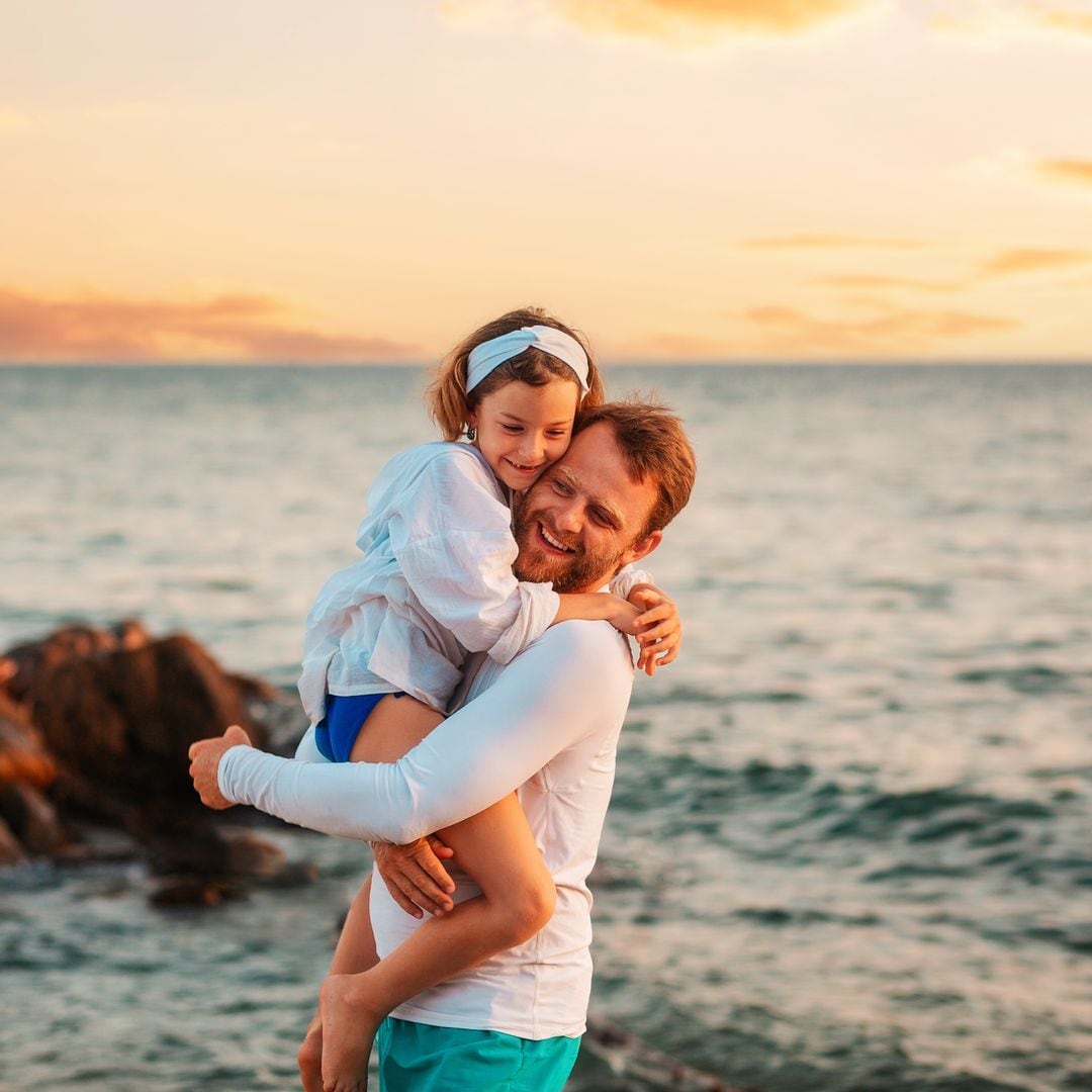 Un padre abraza feliz a su hija porque están pasando un rato divertido durante las vacaciones familiares de verano.
