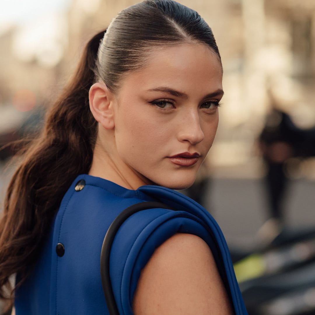 Invitada de street style con estilismo azul y coleta alta
