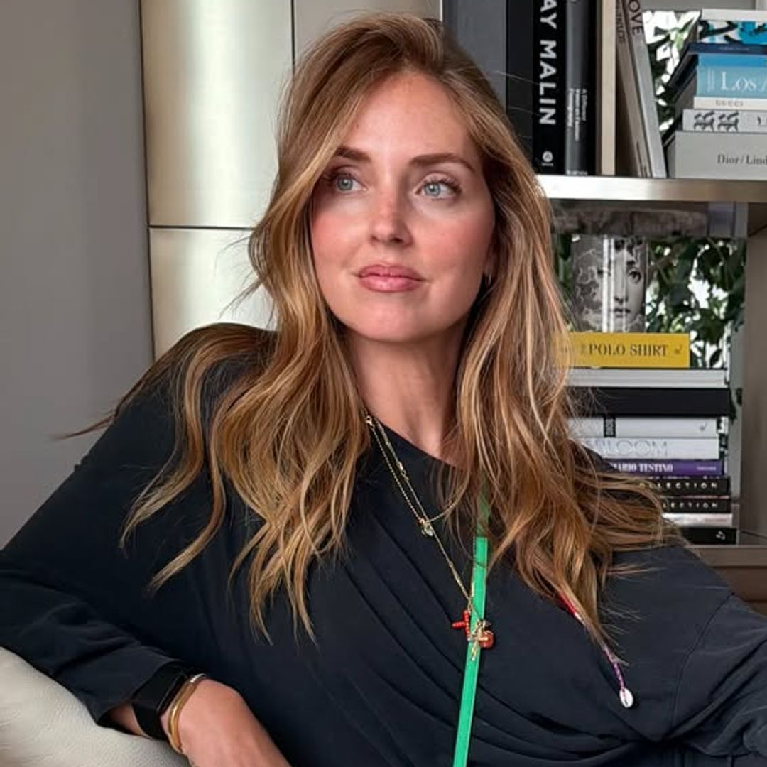 Chiara Ferragni con minivestido negro, bolso verde y un rubio cobrizo sentada en un sofá