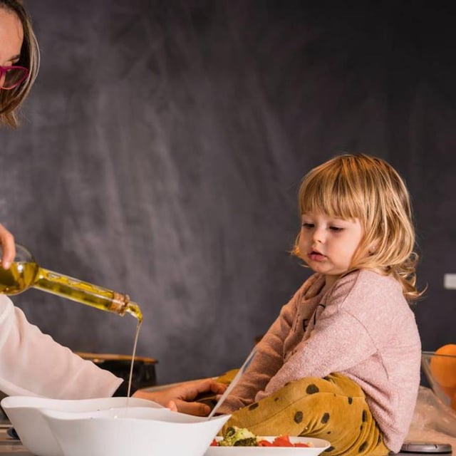 mam cocinando con aceite junto a su hija