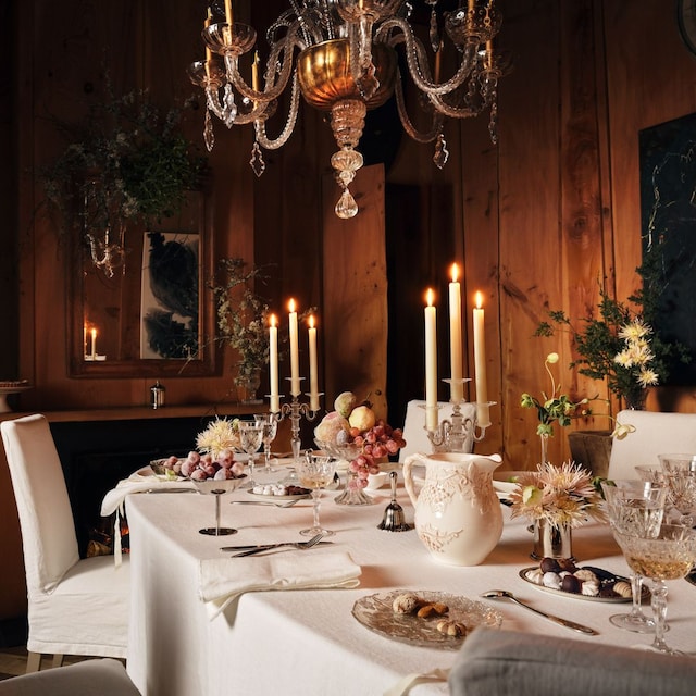 Mesa de Navidad de Zara Home con mantel blanco, lámpara de araña y candelabro