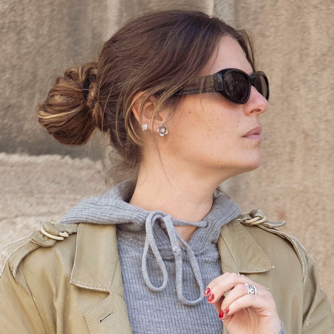Invitada de la Semana de la Moda de Copenhague con gabardina, gafas de sol y sudadera gris