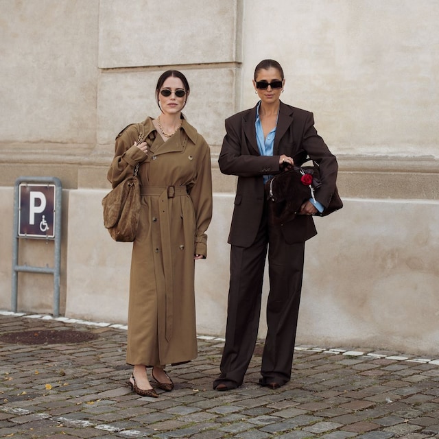 Annabel Rosendahl lleva gabardina larga beige o marrón y bolso marrón y Darja Barannik lleva pantalones marrones, camisa azul y blazer marrón y bolso marrón con accesorios de color rosa fuera del desfile The Garment durante el tercer día de la Semana de la Moda de Copenhague (CPHFW) SS25 el 07 de agosto 2024 en Copenhague, Dinamarca. 