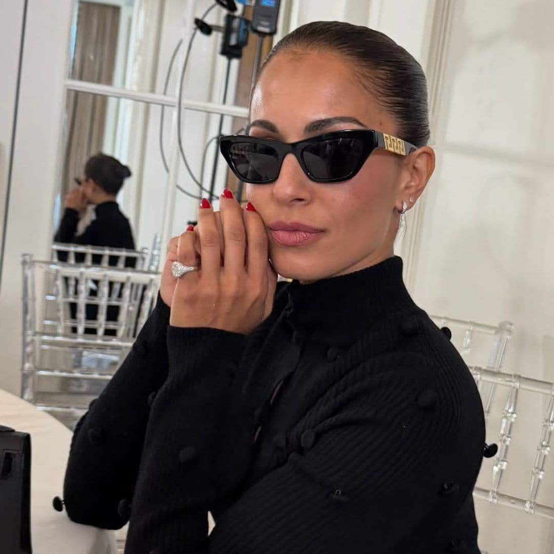 Hiba Abouk con estilismo negro, gafas de sol y uñas rojas en un restaurante