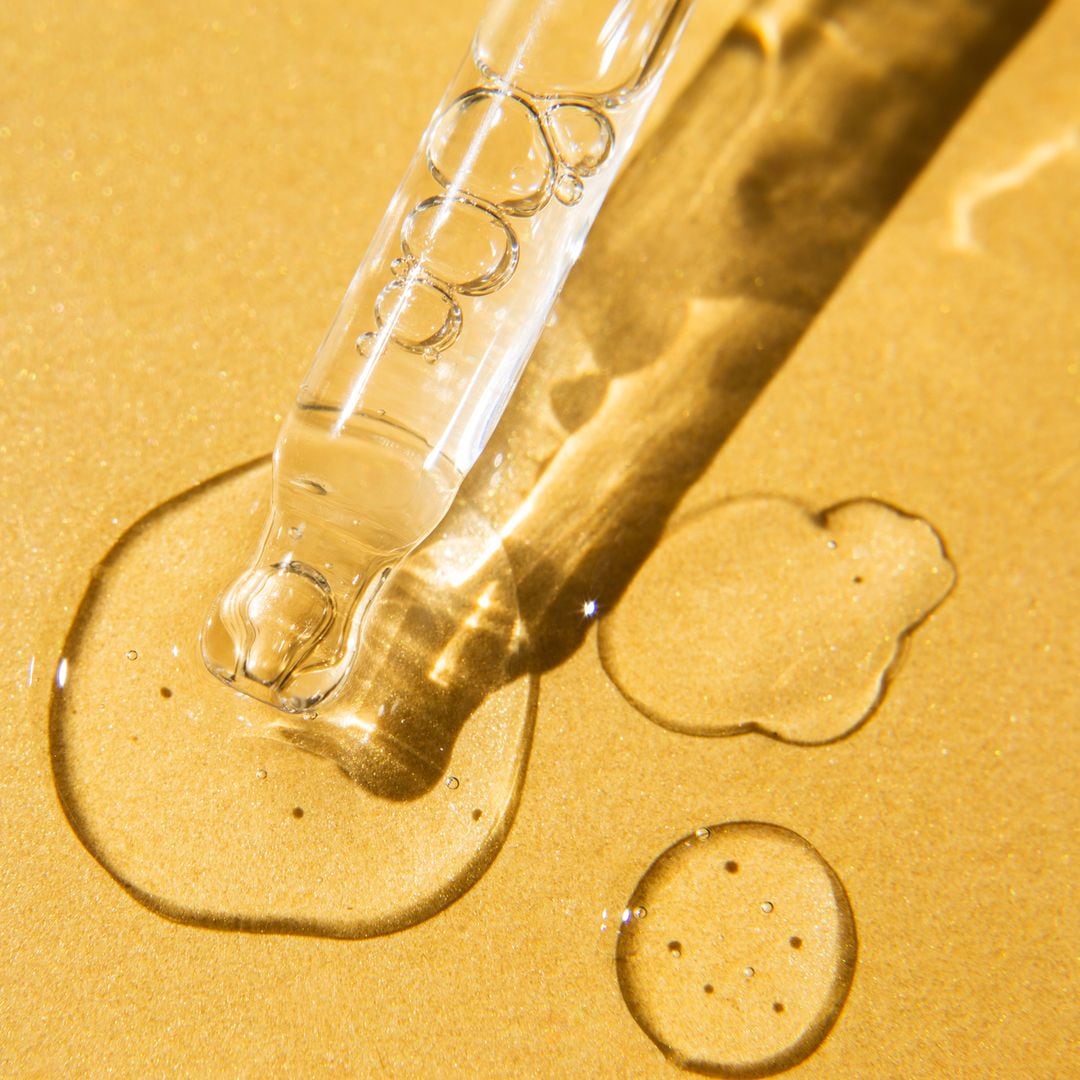 Liquid gel and serum drops nearby pipette on glitter yellow background. Beauty product with peptides, ceramides, hyaluron acid. Flat lay, top view, copy space.