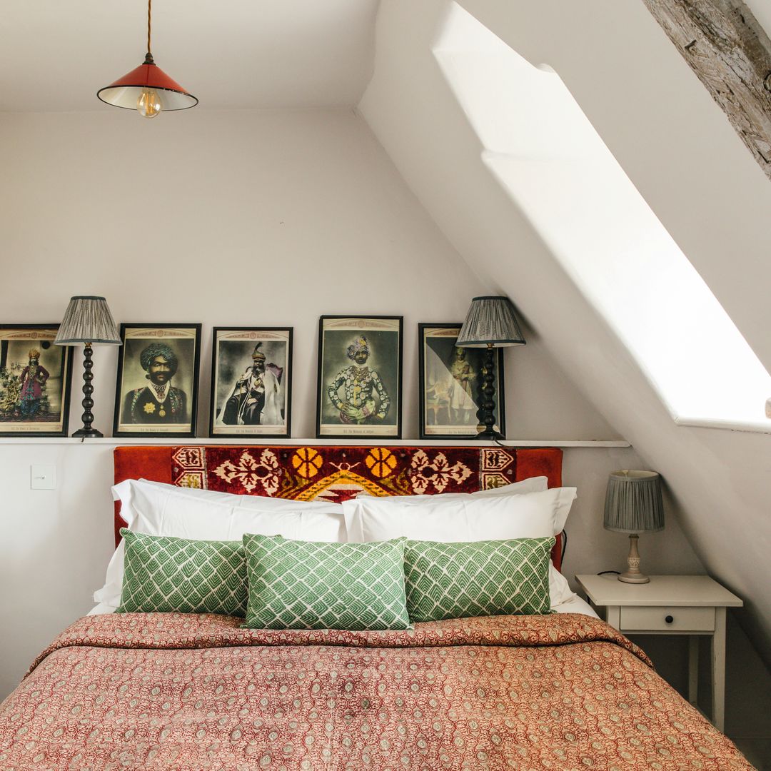 Habitación con cama, almohadas verdes, y cuadros decorativos en la pared.