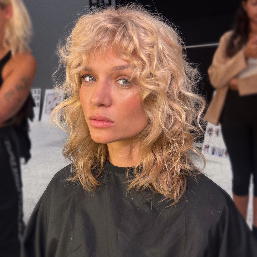 Josephine Skriver con bata de peluquero y pelo rizado