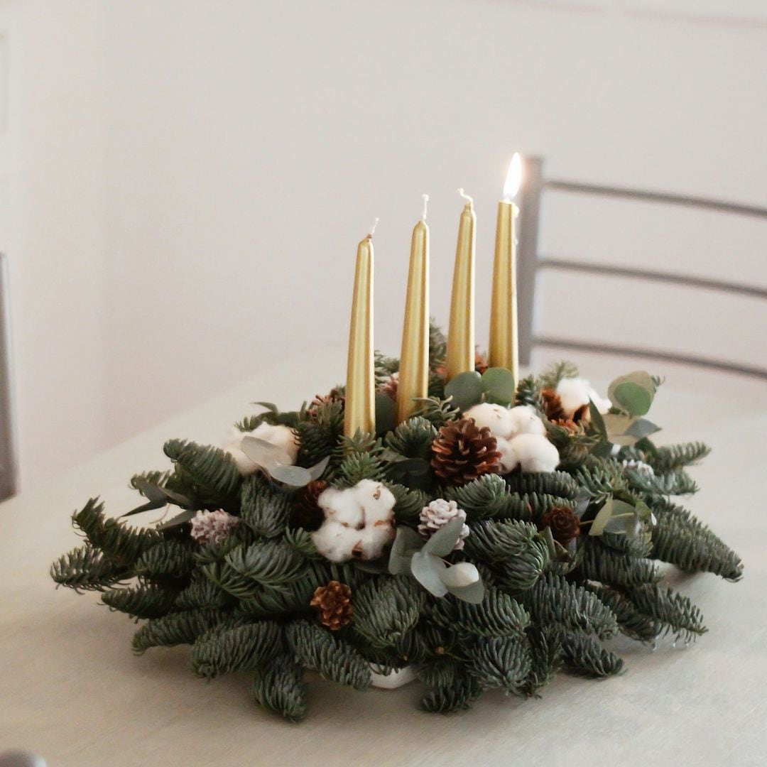 Centro de mesa Navidad con velas doradas y tonos blancos y marrones.